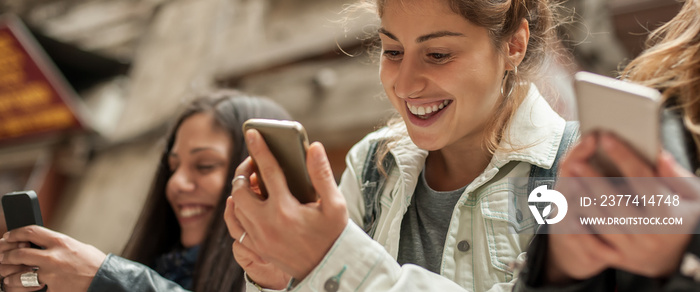 Happy girl friends watching internet social media in cell phone