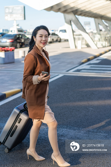 商务女士在机场拉着行李箱