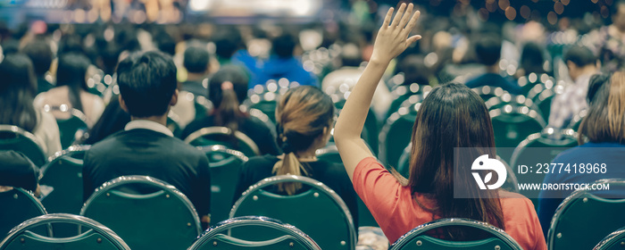 Rear view of Audience in put hand up acton for answer the Speaker question on the stage in the big hall meeting or seminar room, business and education concept,Banner and web page or cover template