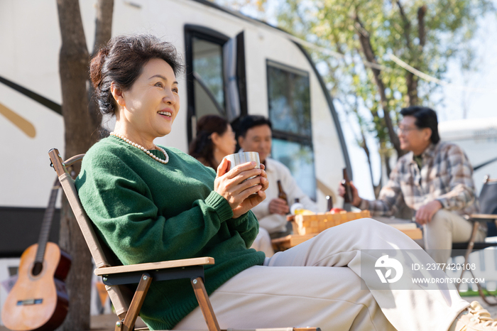 一个老年女人坐在房车露营地喝咖啡