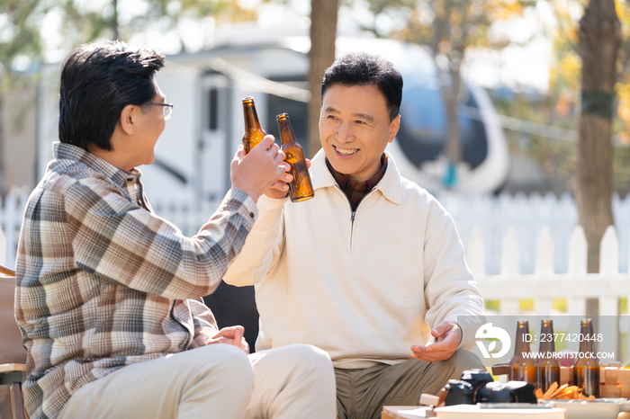 两个老年男人坐在露营地喝啤酒