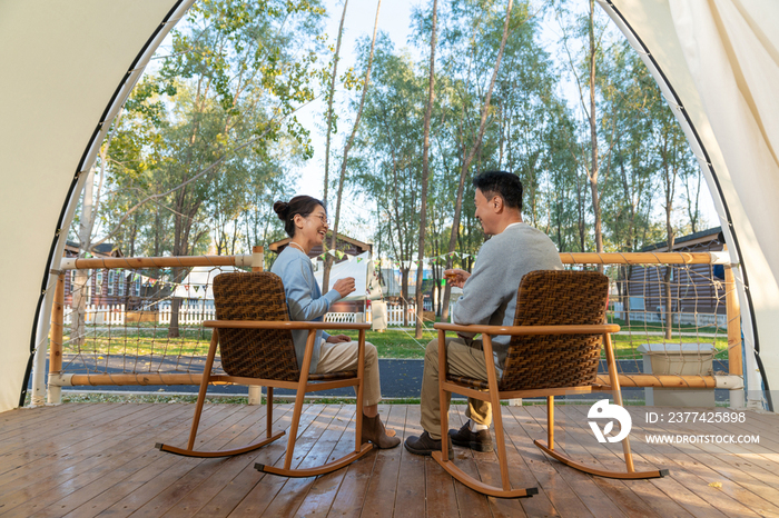 老年夫妻在露营地坐着摇椅喝茶聊天