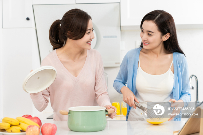 年轻女子在厨房边做饭边和朋友聊天