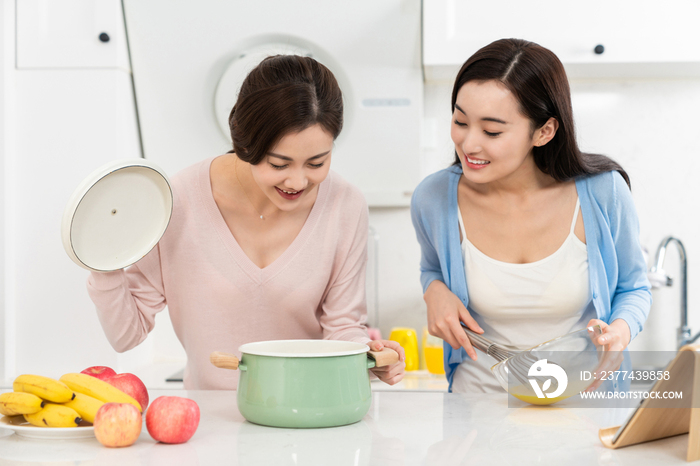 年轻女子在厨房边做饭边和朋友聊天