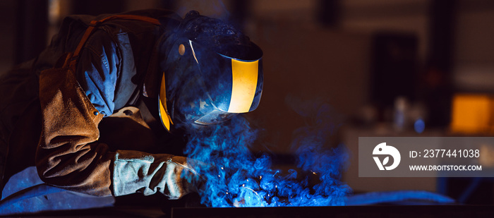 Industrial Welder With Torch and Protective Helmet