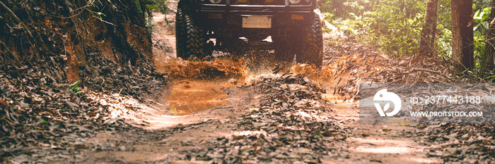 front view of the off-road vehicle Driving through a mud hole, in a forest, on a muddy road