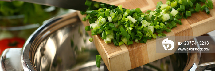 Close up of cook putting onions in a pan in the kitchen at home while making soup. Cooking recipes concept