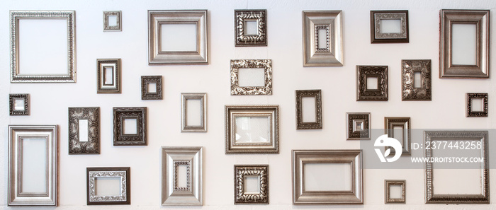 Multiple many blank small picture frames on white wall