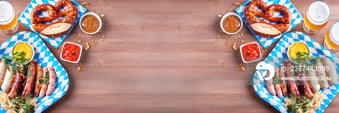 Oktoberfest table with traditional food. Roasted sausages, pretzels, beer, sour cabbage, mustard on wooden background, top view, copy space, web banner, oktoberfest border