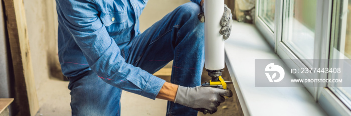 Man in a blue shirt does window installation. Using a mounting foam BANNER, long format