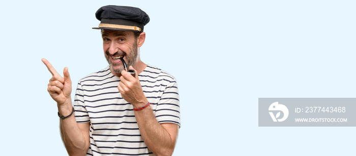 Sailor captain man smoking a tobacco pipe pointing away side with finger isolated over blue background