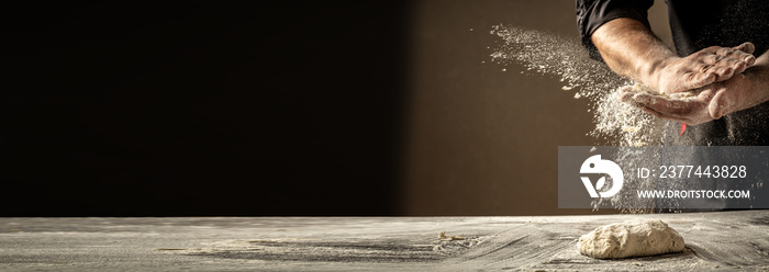 Photo of flour and men hands with flour splash. Cooking bread. Kneading the Dough. Isolated on dark background. Empty space for text