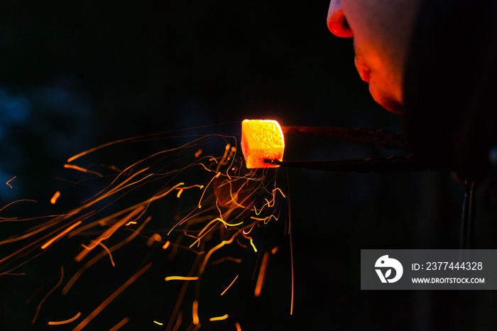 Shisha hookah, red hot coals. Man holding tongs charcoal and blowing on it. flying sparks.