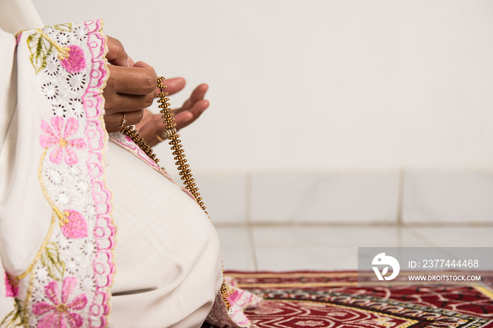 Muslim woman praying close up image of hands as she holds prayer beads,tasbih.