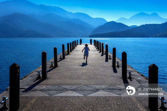 Little girl running on pathway in Sun moon lake, Taiwan.