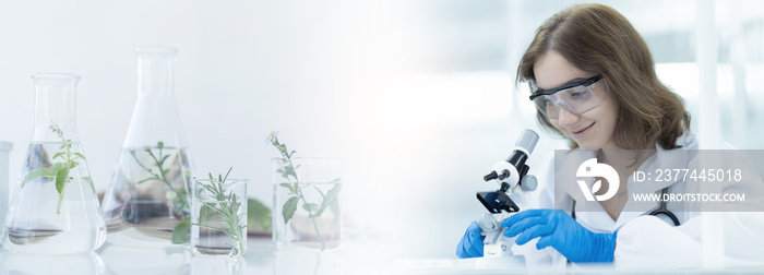 Woman doctor researching through microscope doing analysis for germs and bacteria of test sample in the laboratory. Female scientist working with biotechnology research with microscope