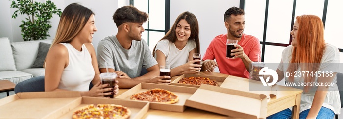 Group of young people smiling happy eating italian pizza sitting on the table at home