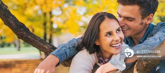 Portrait of smiling young couple outdoors in autumn having fun t