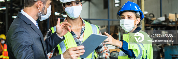 Industrial engineers and businessman in suite and safety helmet wearing mask working in factory, planning, discussing and training workers with tablet in metalwork place , teamwork and team concept