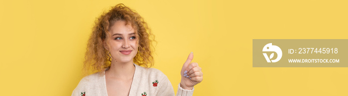 Close-up portrait of attractive surprised girl, showing thumbs up gesture. Success luck concept.