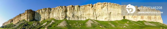 Wide panorama of precipitous edge of limestone plateau against sky