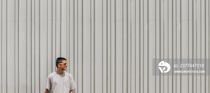 young man in sunglasses in summer on the street wall