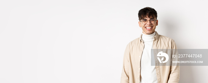 Real people. Natural portrait of happy guy smiling and laughing, looking upbeat at camera, standing in glasses on white background