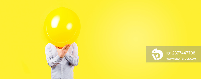 man holding yellow balloon. Positive thinking concept, image on a yellow background, panoramic mock-up with space for text