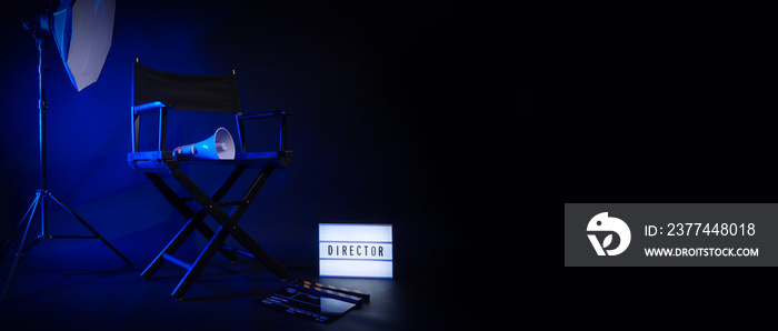 Director chair with cinema lightbox sign Director text on it and clapperboard megaphone and black background studio. Director seat on video production or filming set used in film industry. Real no 3D