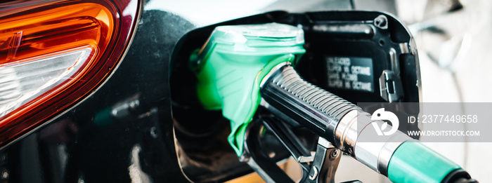 Man pumping petrol at gas station into vehicle. Hand holding a pistol  pump. Banner.