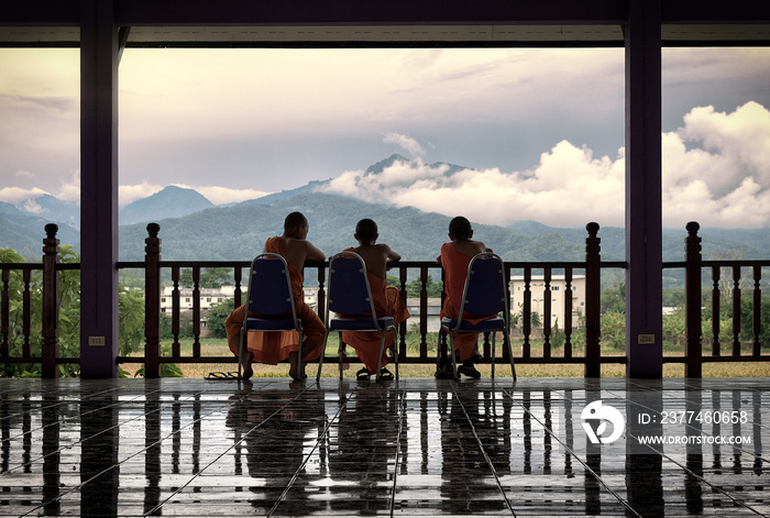 three young buddhist monks looking the mountains in a buddhist monastery in thailand