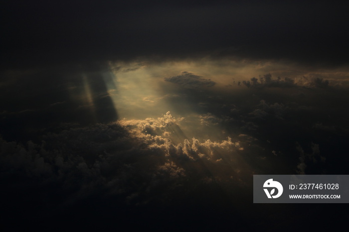 Rays of light shining through dark clouds on another cloud layer for background