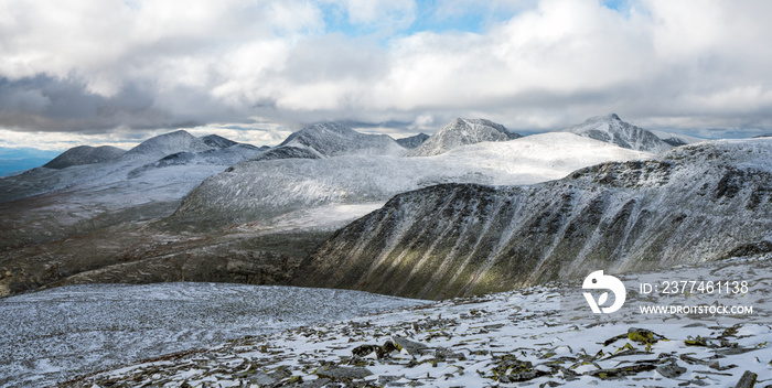 Panorama image and panoramic view over the mountain peaks in Rondane and Dovrefjell national parks in Norway. Snowy, foggy and frozen landscape during winter. Hiking and nature concept.