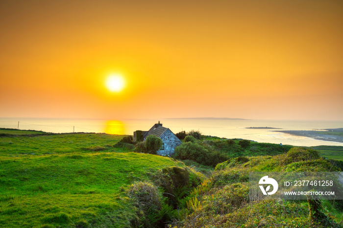 Irish cottage house near the ocean at sunset