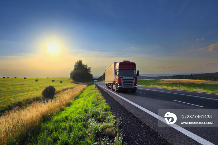 Red truck transport on the road at sunset and cargo