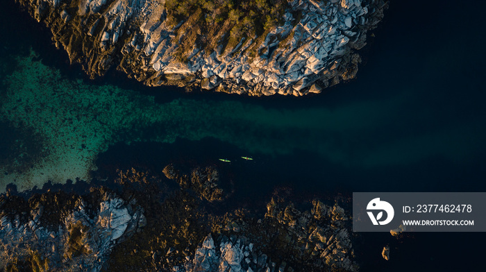 Aerial picture of kayaks between islands. Active summer vacation, north of norway located in lofoten islands. Two people kayaking surrounded beautiful landscape and turquoise sea. Distance picture