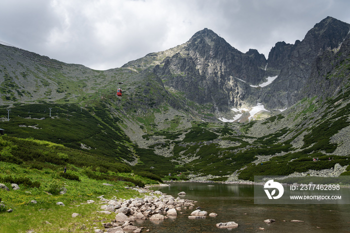 Scenic view of Skalnate Pleso (Rocky Tarn) and cable car heading to Lomnicky Stit peak in High Tatra mountains, Slovakia. Beautiful clean nature in Central Europe, cloudy day in summer