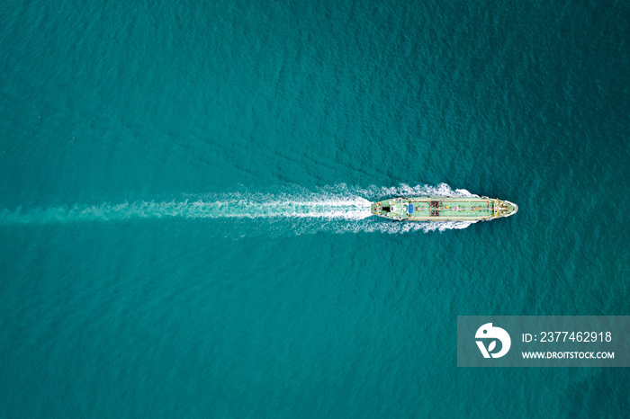 Aerial top view Oil ship tanker full speed with beautiful wave and splash water in line of transportation from refinery on the sea.