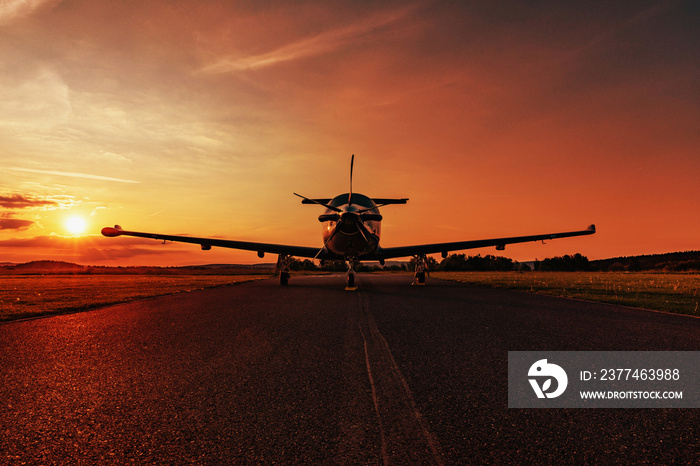 A single-engine plane is parked on the runway, bathed in the evening sun. Beautiful color view of the plane.