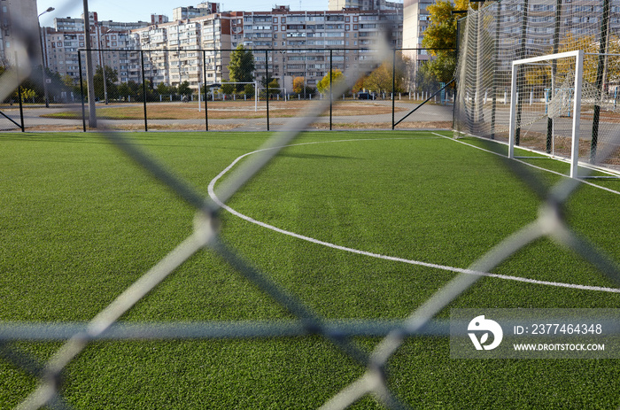 Lawn field for playing football behind the green fence mesh. Close-up of soccer field with green grass