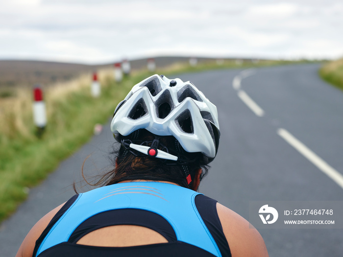 Rear view of female cyclist on country road