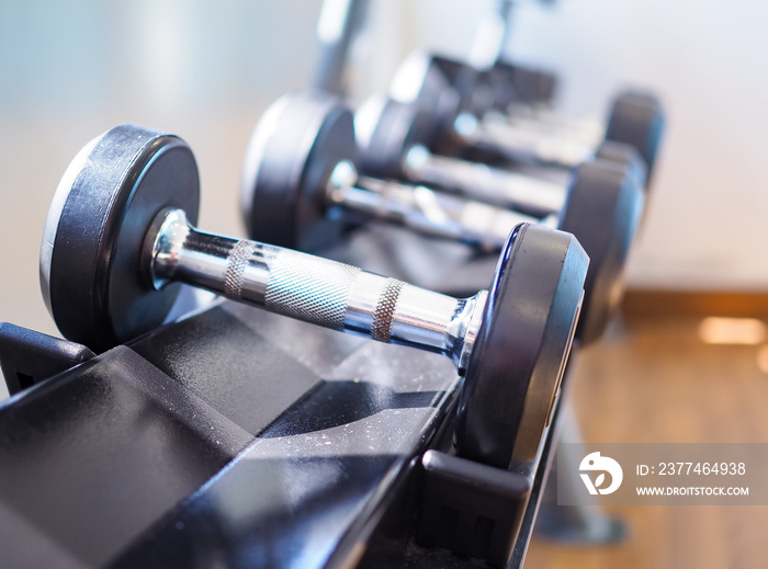 Many dumbbells on the shelves in the gym. It​ is​ a short bar with a weight at each end, used for making the arm and shoulder muscles stronger.
