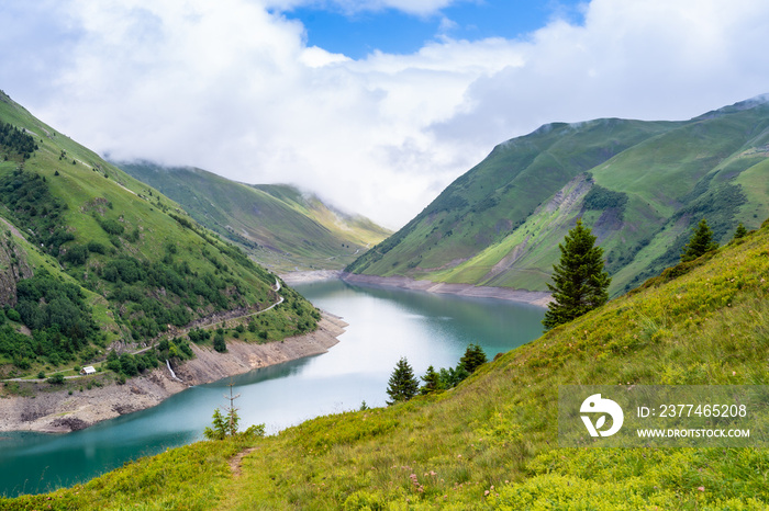 Beautiful summer panorama of the mountain lake in Vaujany, France. Cloudy  view in the French Alps, Europe. Scenery landscape of high plateau.