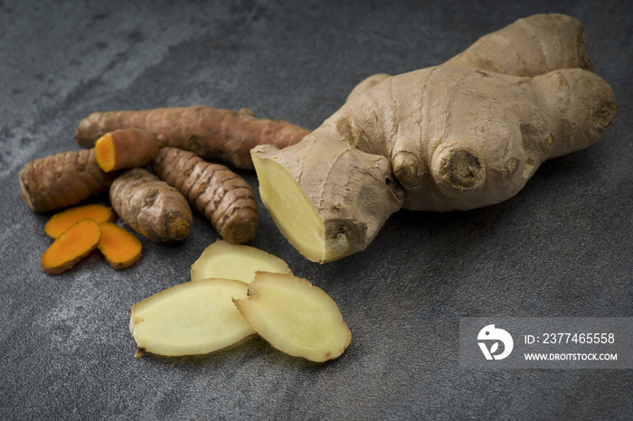 turmeric slices and ginger root sliced on gray background