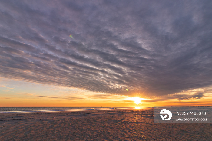 Rippled altocumulus clouds in the sky as the sun sets over a beach. Jones Beach New York.