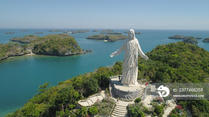 Statue of Jesus Christ on Pilgrimage island in Hundred Islands National Park, Pangasinan, Philippines. Aerial view of group of small islands with beaches and lagoons, famous tourist attraction