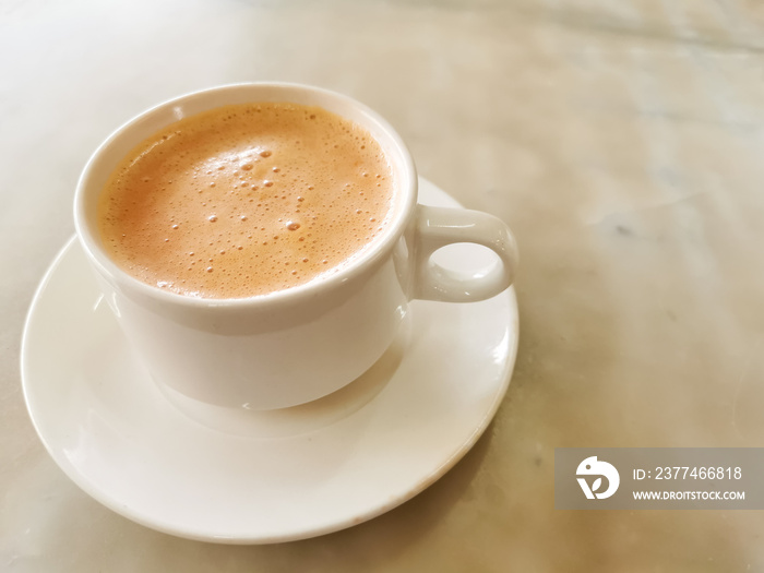 Tea with milk in a cup locally popularly known as Teh Tarik on the table.