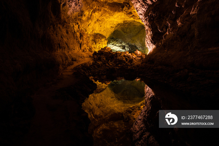 Optical reflection effect on cave lava tube illuminated in Canary Islands. Geological cavern formation, tourist attraction concepts