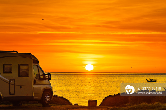 Camper vehicle on beach at sunrise