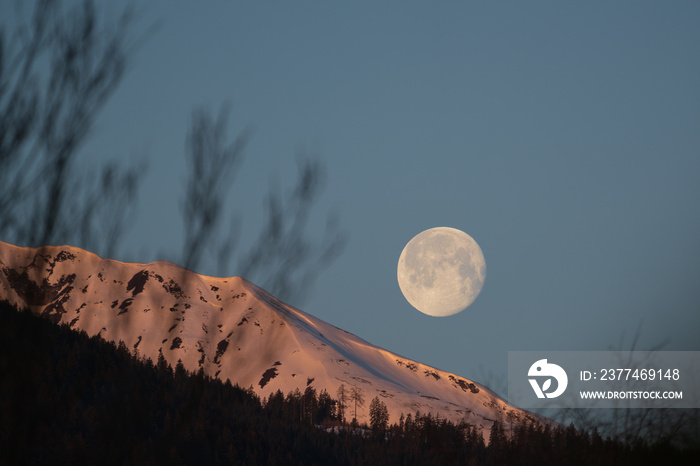 at sunrise on the mountains and the moon goes down